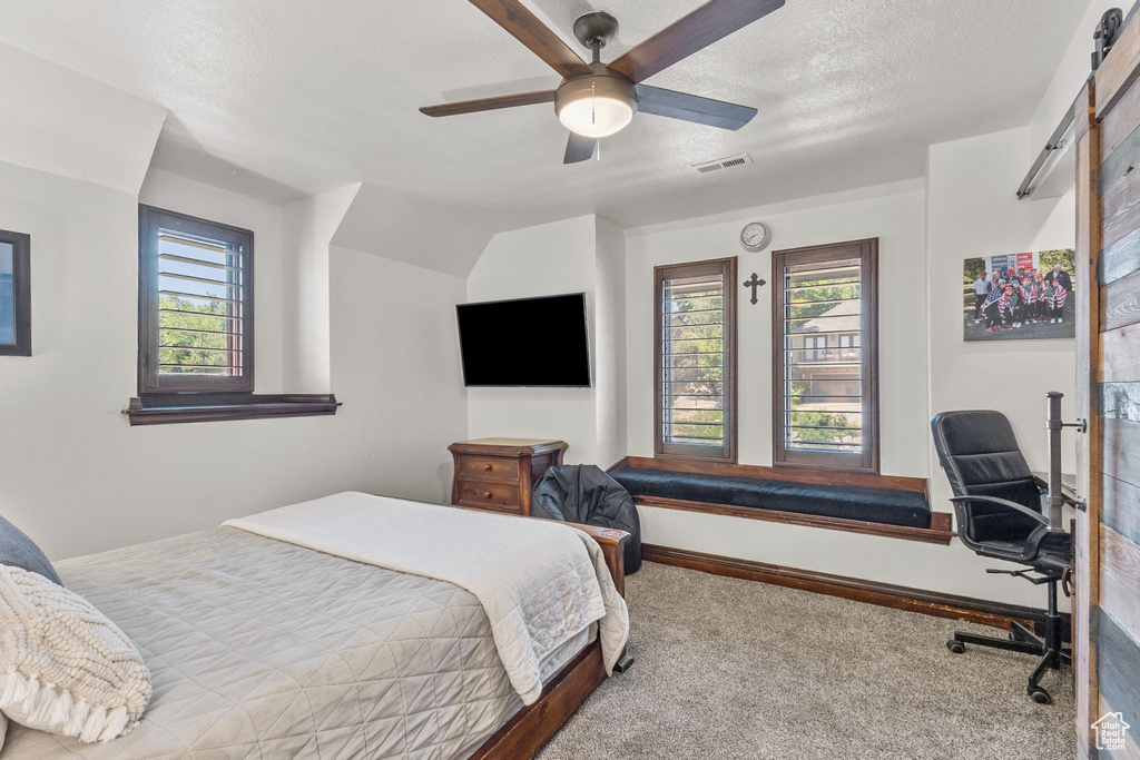 Carpeted bedroom featuring a ceiling fan, a textured ceiling, and an office area