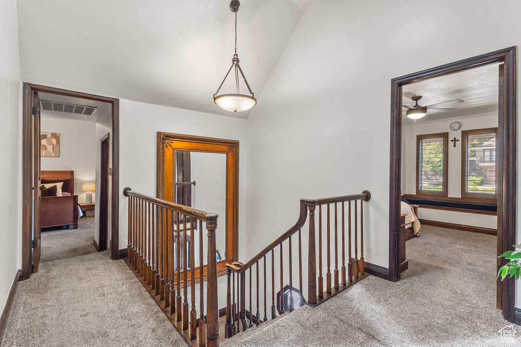Hall with an upstairs landing, carpet flooring, and lofted ceiling