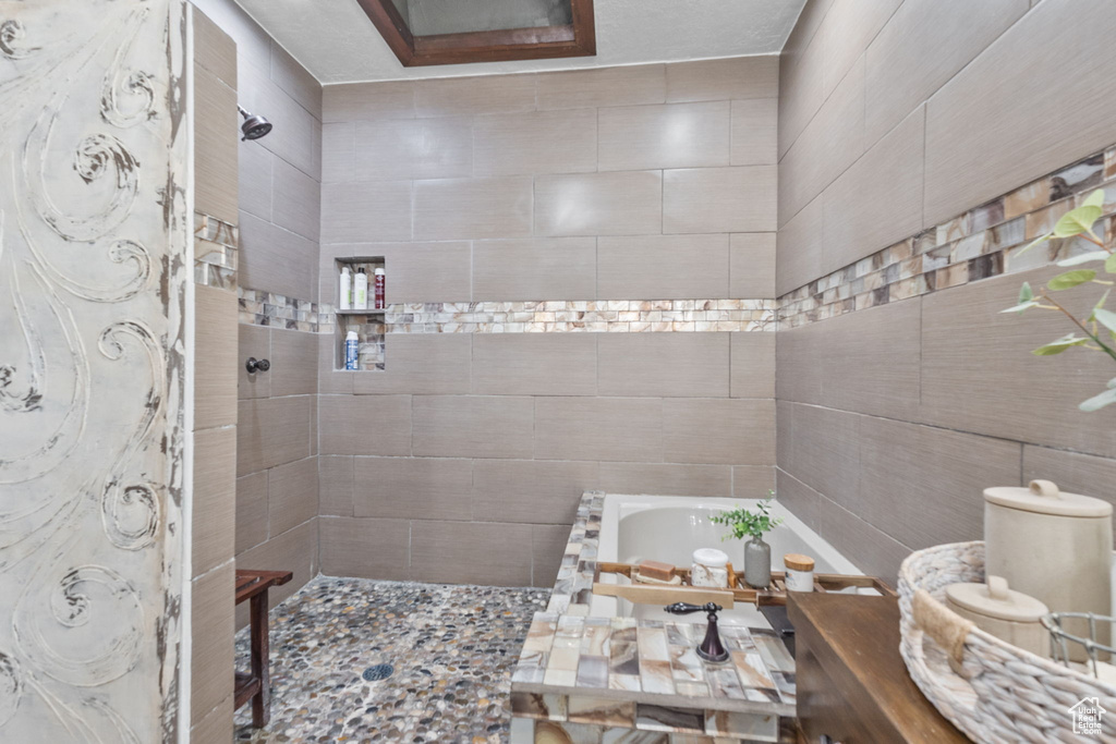 Bathroom featuring a tile shower and a tub