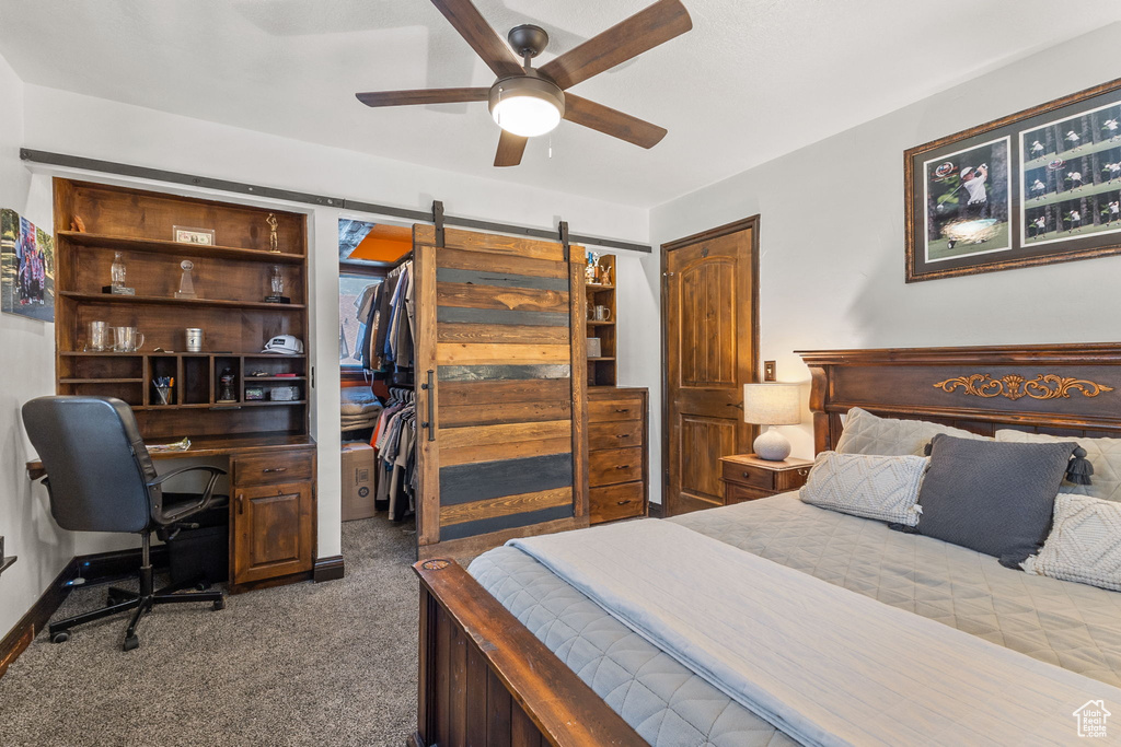 Carpeted bedroom with an office area and ceiling fan