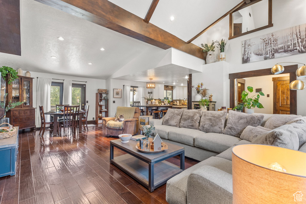 Living area with dark wood-style flooring, beamed ceiling, high vaulted ceiling, and recessed lighting