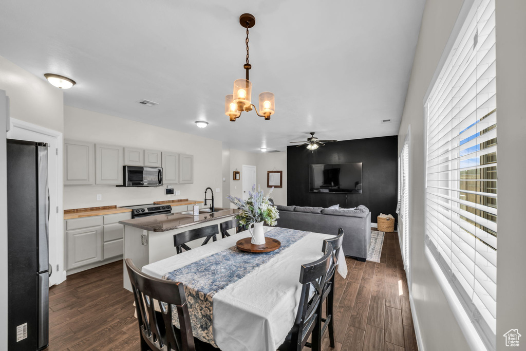 Dining area with a chandelier, dark wood finished floors, and ceiling fan