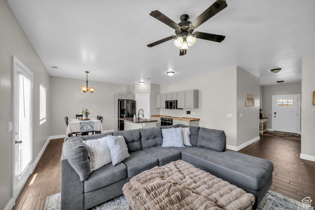 Living area featuring a chandelier, wood finished floors, healthy amount of natural light, and ceiling fan