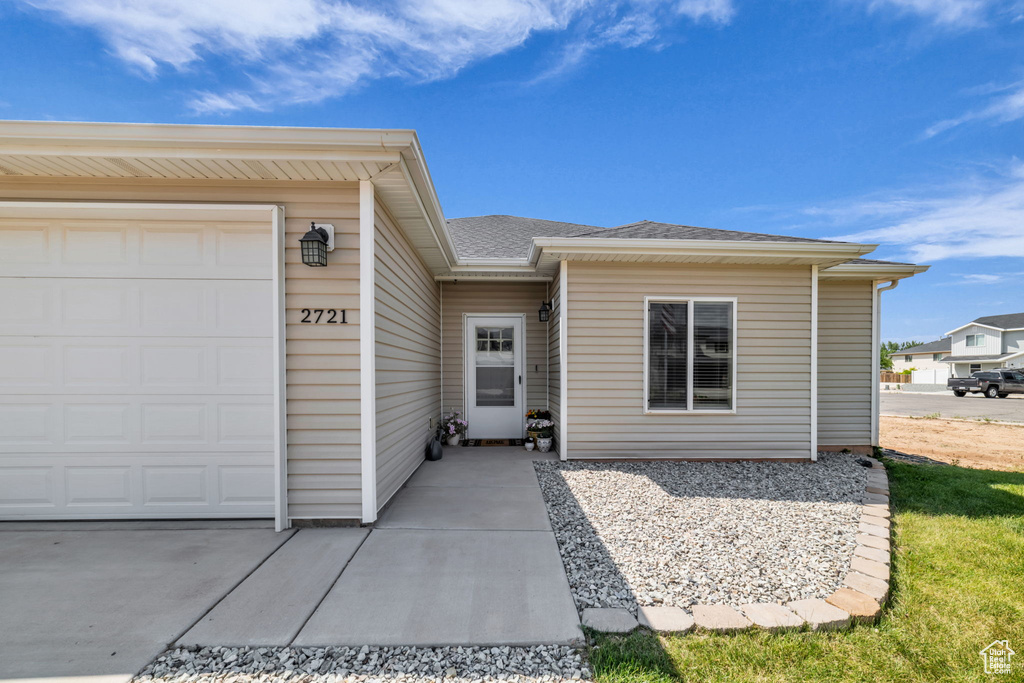Property entrance featuring an attached garage and roof with shingles