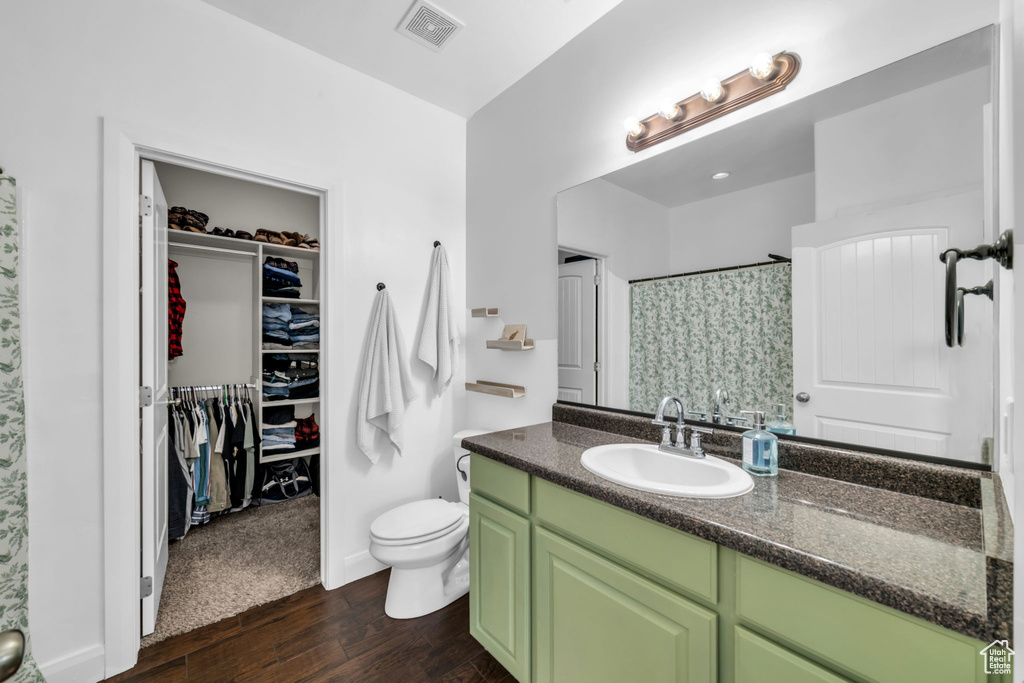 Full bathroom featuring vanity, wood finished floors, a shower with curtain, and a walk in closet