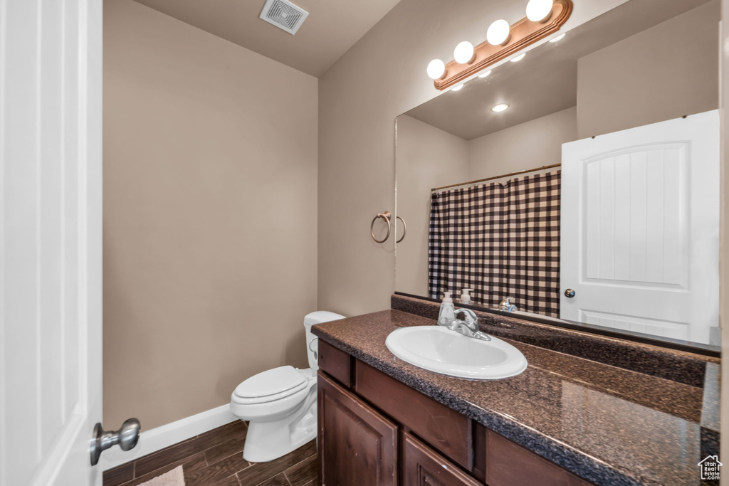 Full bathroom featuring vanity, wood finished floors, and curtained shower