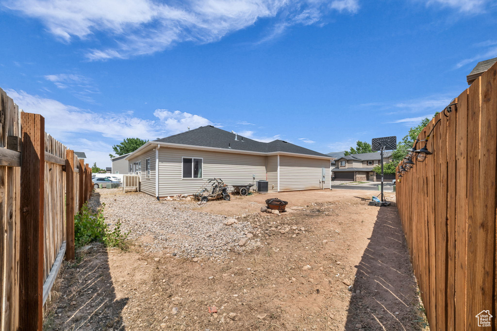 Back of house with a fenced backyard and a shingled roof