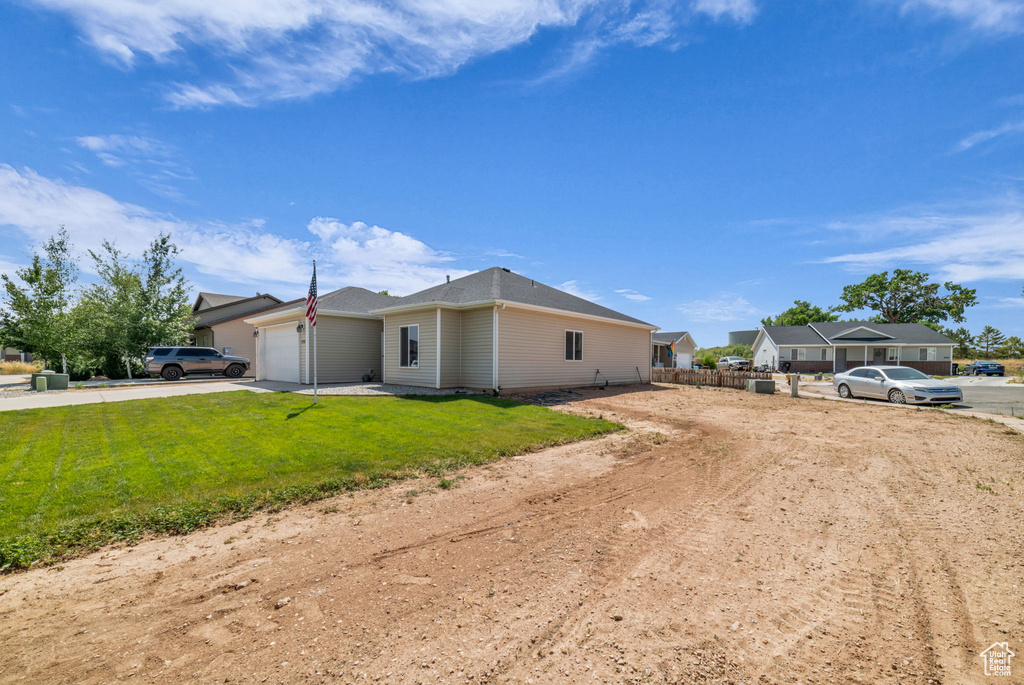 View of front of home with a garage, concrete driveway, and a front lawn
