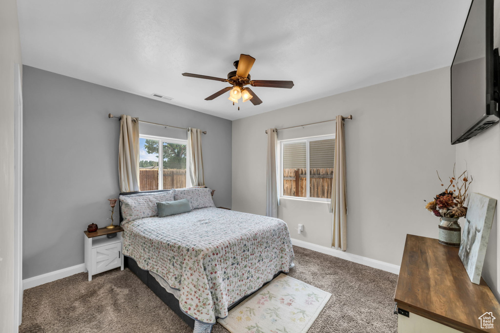 Bedroom with dark colored carpet and a ceiling fan