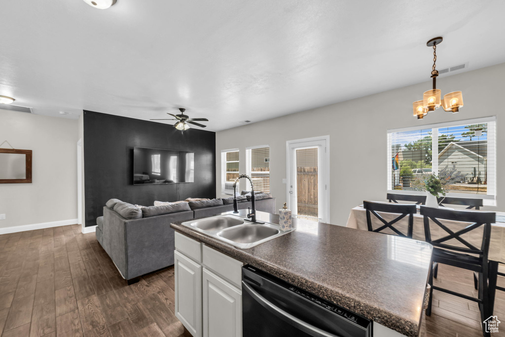 Kitchen with dishwasher, ceiling fan, dark countertops, dark wood-type flooring, and white cabinets
