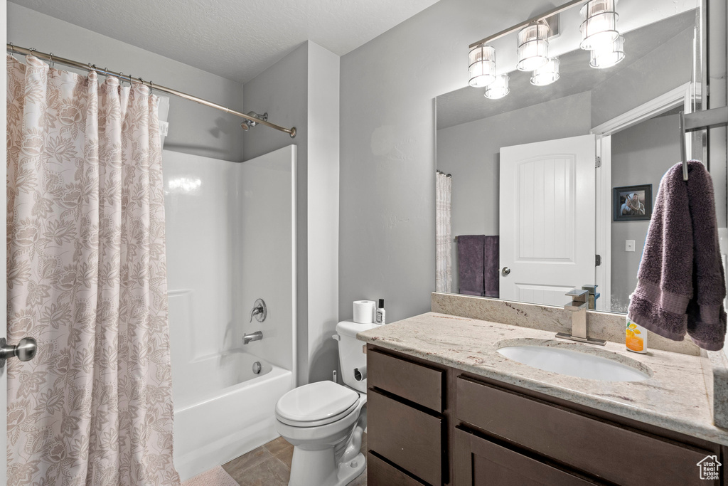 Bathroom featuring vanity, shower / bath combo, and tile patterned flooring