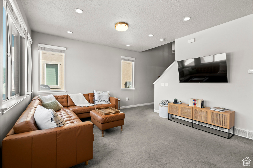 Carpeted living room featuring recessed lighting and a textured ceiling