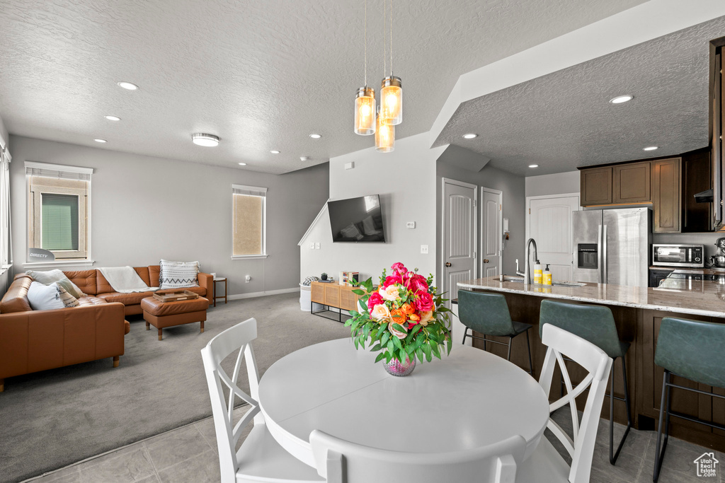 Dining space with a textured ceiling, light carpet, and recessed lighting