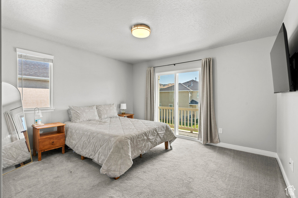 Bedroom with access to exterior, carpet floors, and a textured ceiling