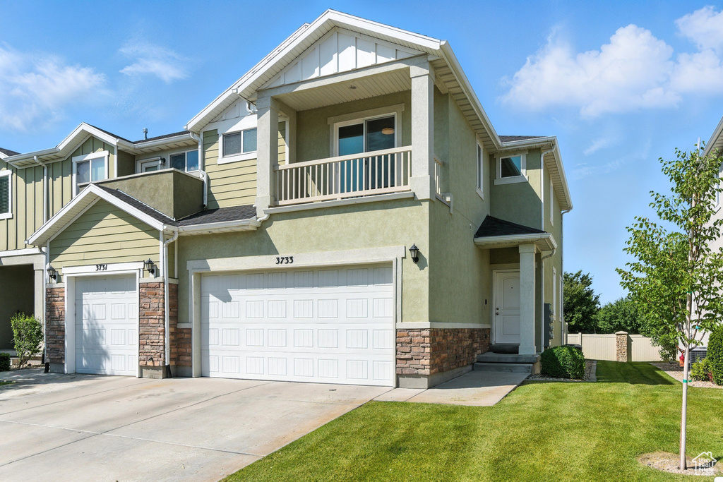 View of property featuring stone siding, a front lawn, stucco siding, and an attached garage