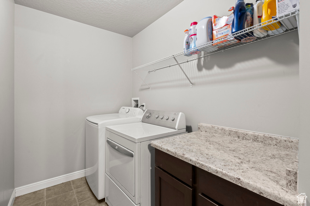 Laundry room with independent washer and dryer and a textured ceiling