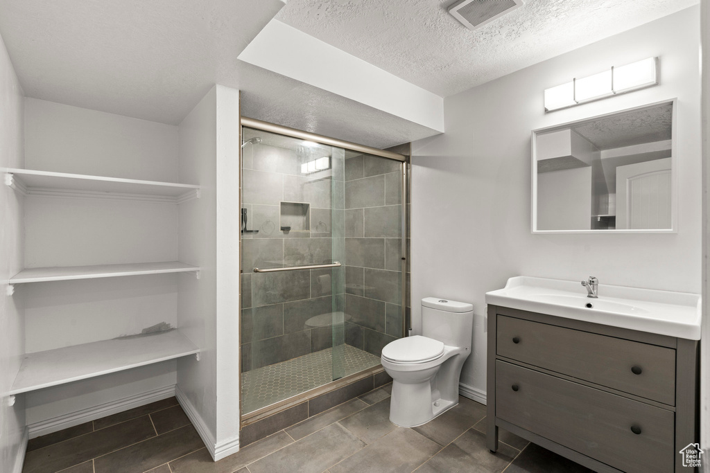 Bathroom featuring vanity, a shower stall, a textured ceiling, and tile patterned flooring