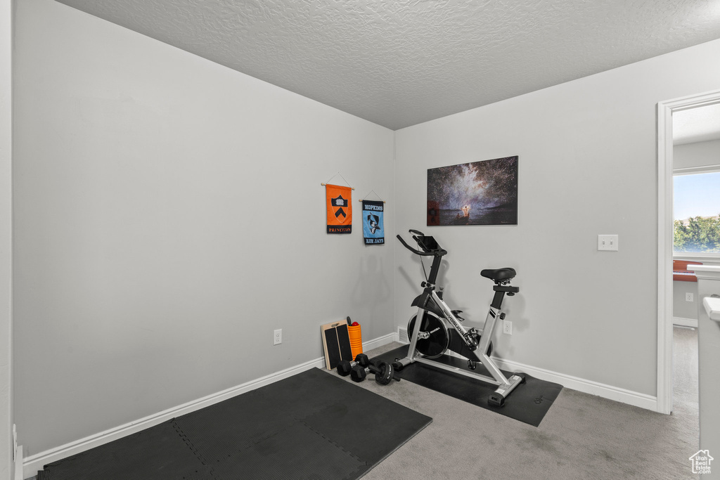 Workout area with a textured ceiling and baseboards