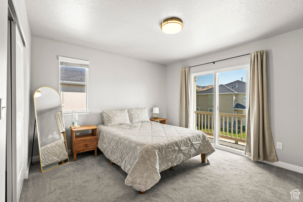 Bedroom with access to exterior, carpet flooring, and a textured ceiling
