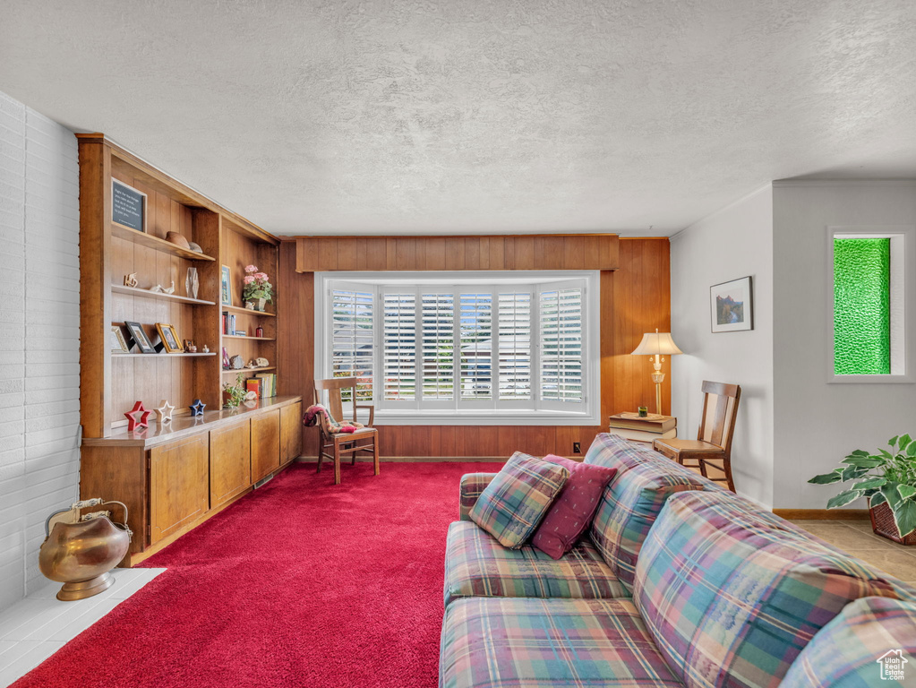Carpeted living area with wood walls and a textured ceiling