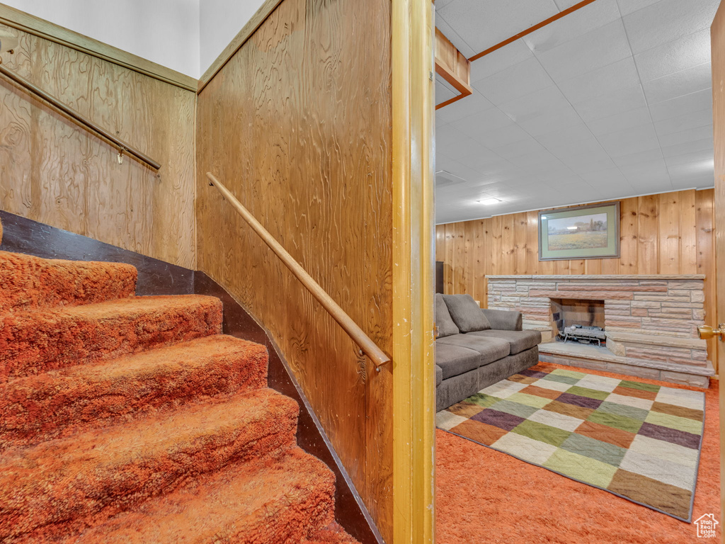 Stairs featuring wood walls, carpet, and a fireplace