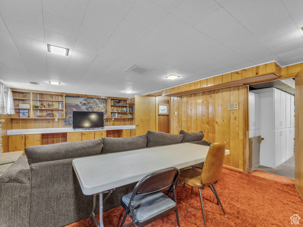 Carpeted living area featuring wooden walls and built in shelves