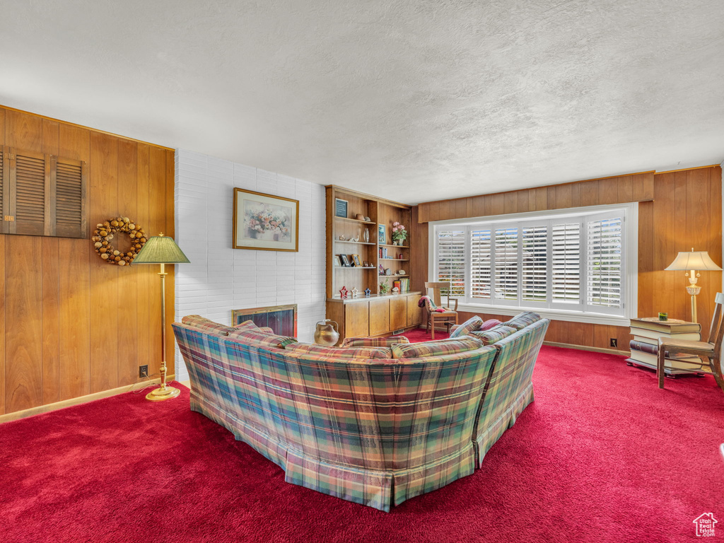 Carpeted living area featuring wooden walls and a textured ceiling
