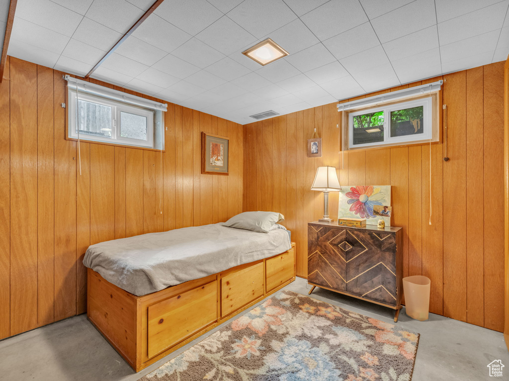 Bedroom with concrete floors and wood walls