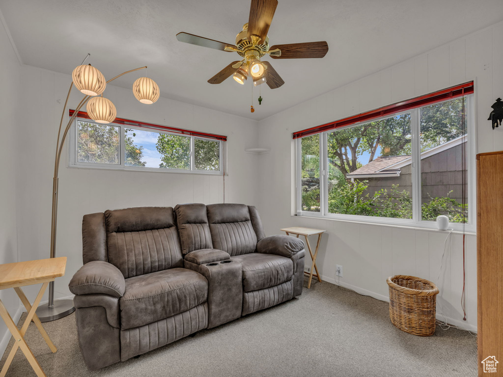 Carpeted living area featuring ceiling fan and baseboards