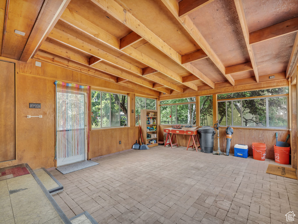 Unfurnished sunroom with wooden walls and brick patterned flooring