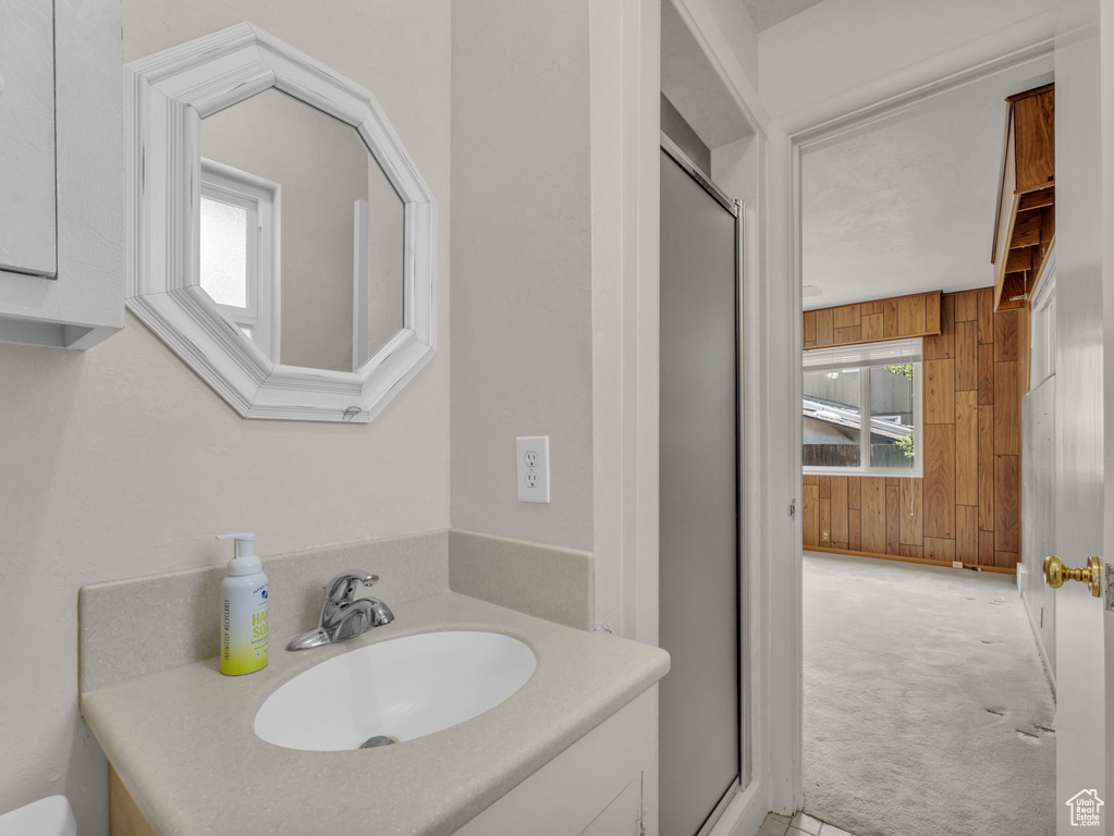 Bathroom featuring wood walls, vanity, and a stall shower