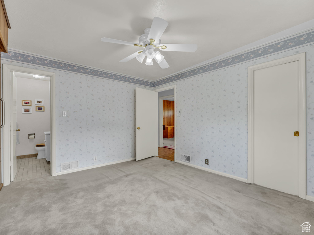 Carpeted spare room featuring a ceiling fan and wallpapered walls