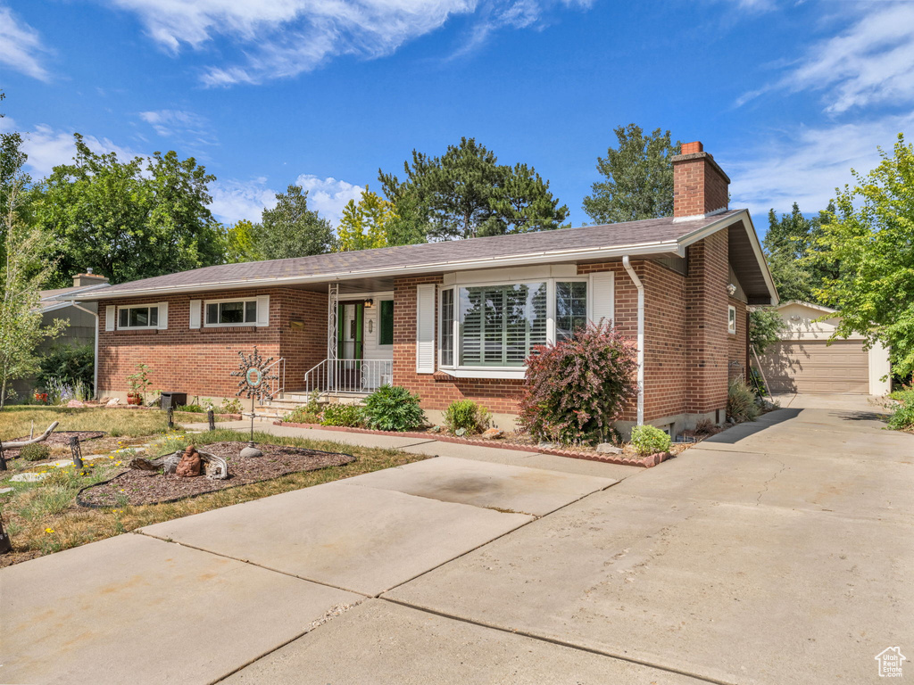 Ranch-style house featuring brick siding, a chimney, and an outbuilding