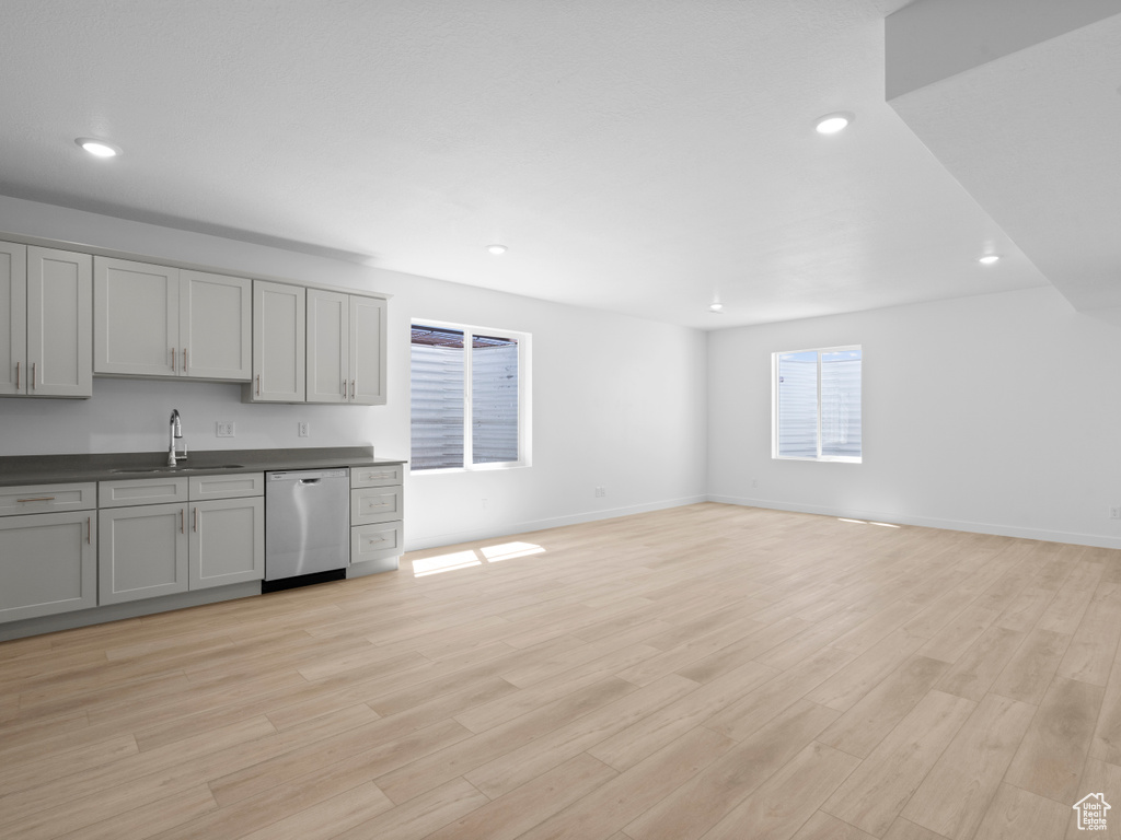Kitchen with dishwasher, dark countertops, gray cabinetry, light wood finished floors, and open floor plan