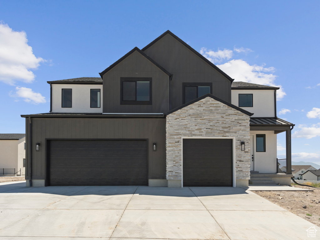 Contemporary house featuring driveway, a standing seam roof, a garage, and a metal roof