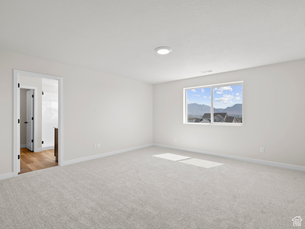 Empty room featuring light carpet and baseboards