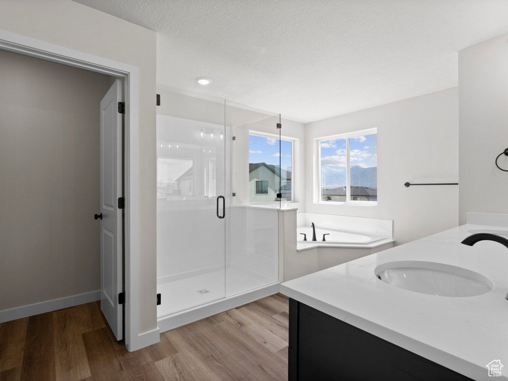 Full bathroom with a stall shower, wood finished floors, vanity, and a bath