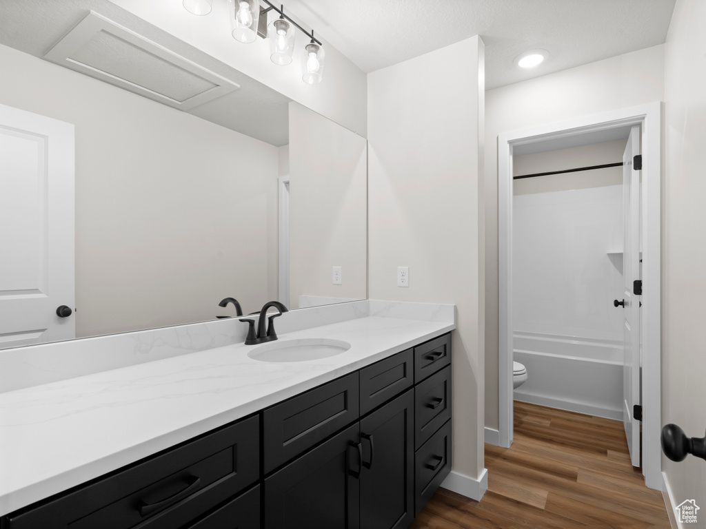 Full bath with vanity, wood finished floors, bathtub / shower combination, and recessed lighting