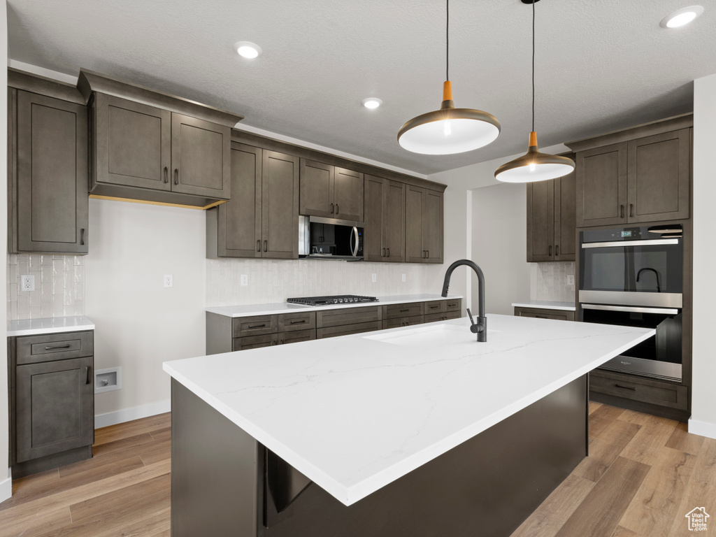 Kitchen with appliances with stainless steel finishes, decorative backsplash, light wood-type flooring, and recessed lighting