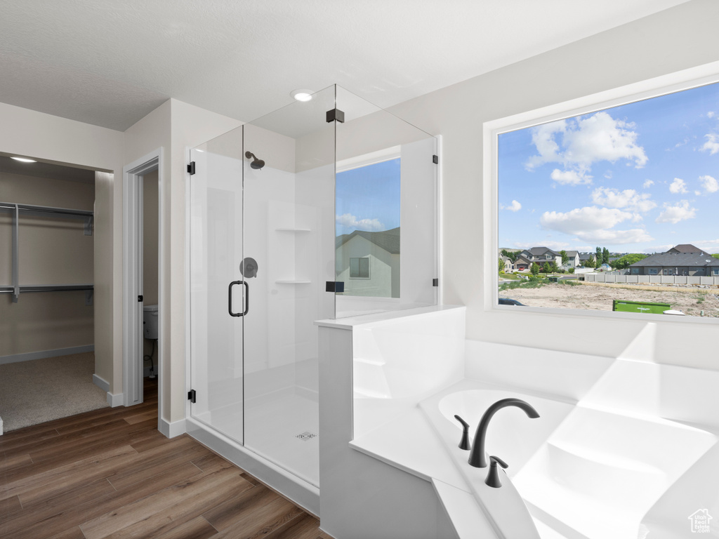 Full bath with a shower stall, wood finished floors, a garden tub, and a walk in closet