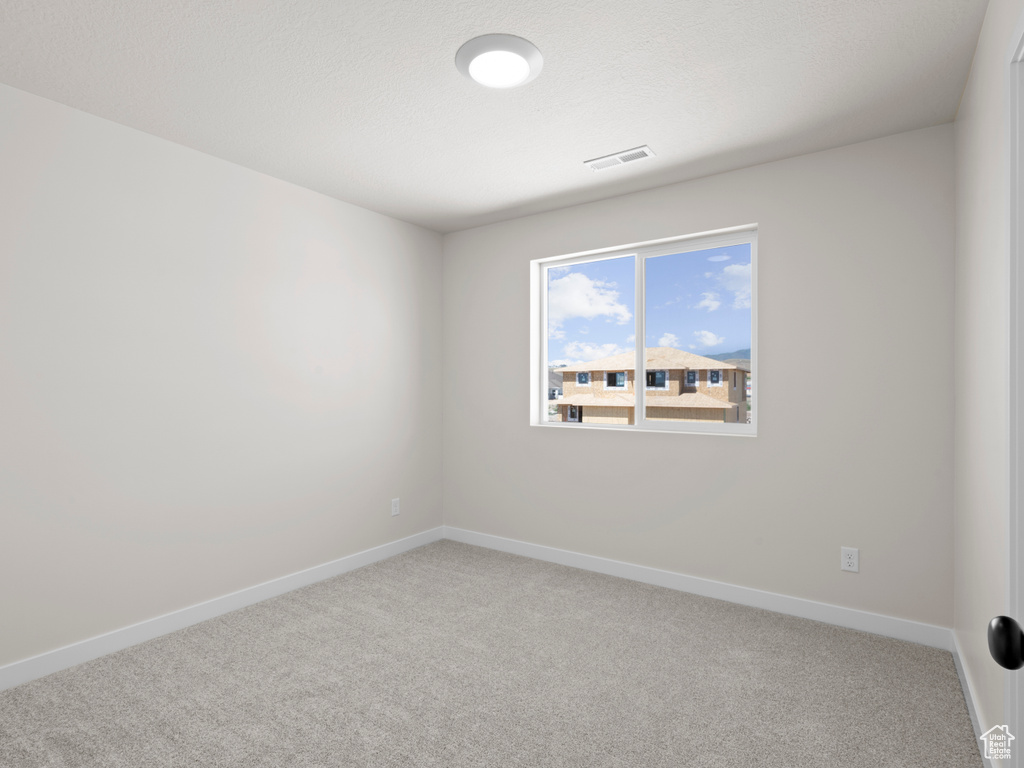 Empty room featuring light carpet and baseboards