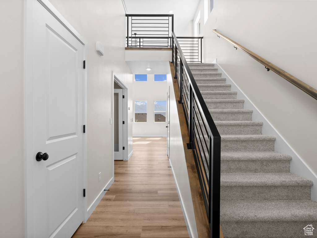Stairway featuring wood finished floors and a towering ceiling