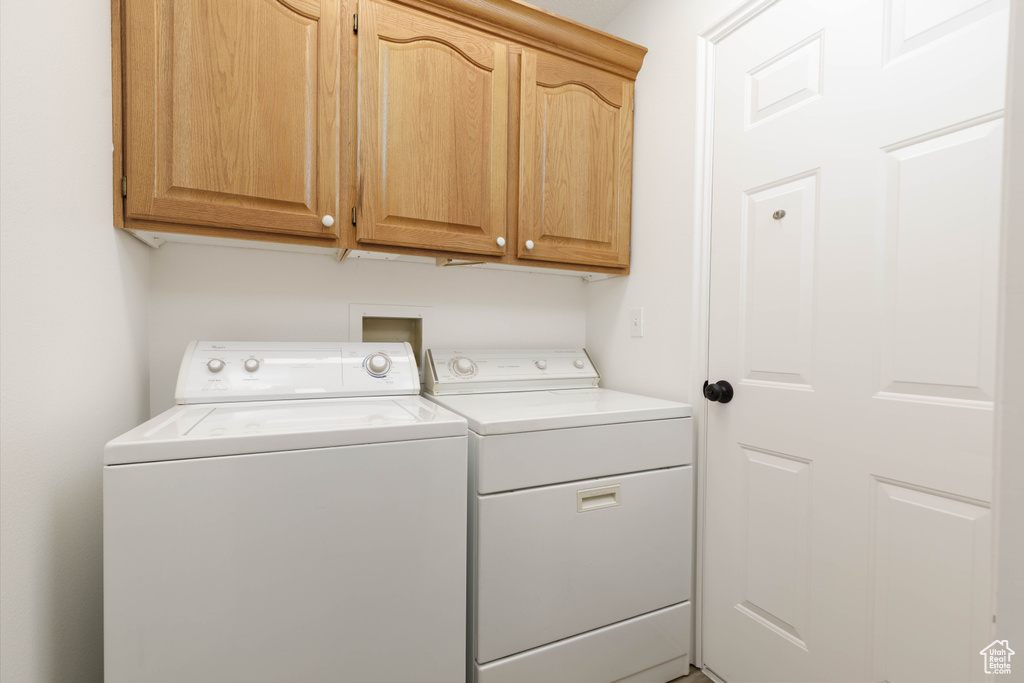 Washroom with washer and clothes dryer and cabinet space