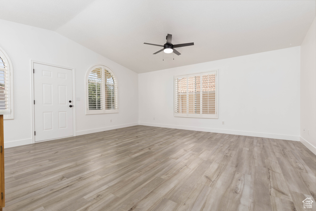 Unfurnished room with a ceiling fan, light wood-style flooring, and vaulted ceiling