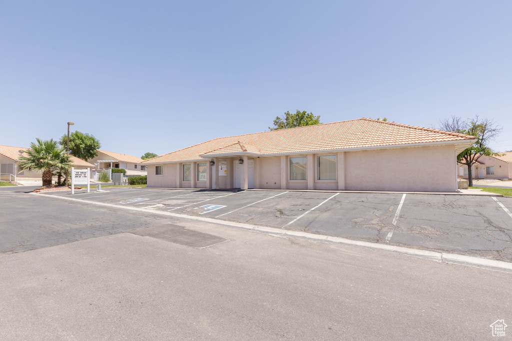 Ranch-style house featuring uncovered parking, a tile roof, and stucco siding