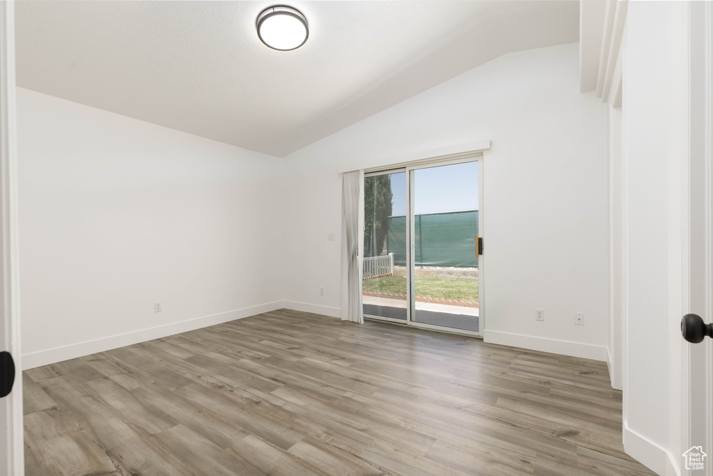 Unfurnished room featuring lofted ceiling and light wood-style flooring