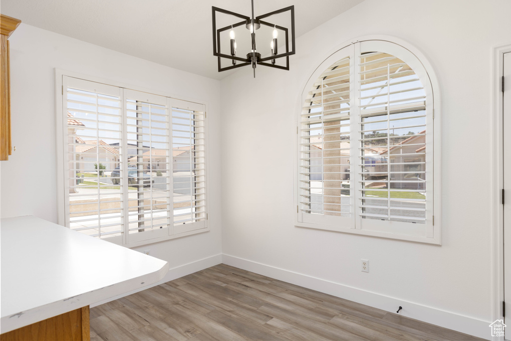 Unfurnished dining area featuring plenty of natural light, light wood-style flooring, and a chandelier