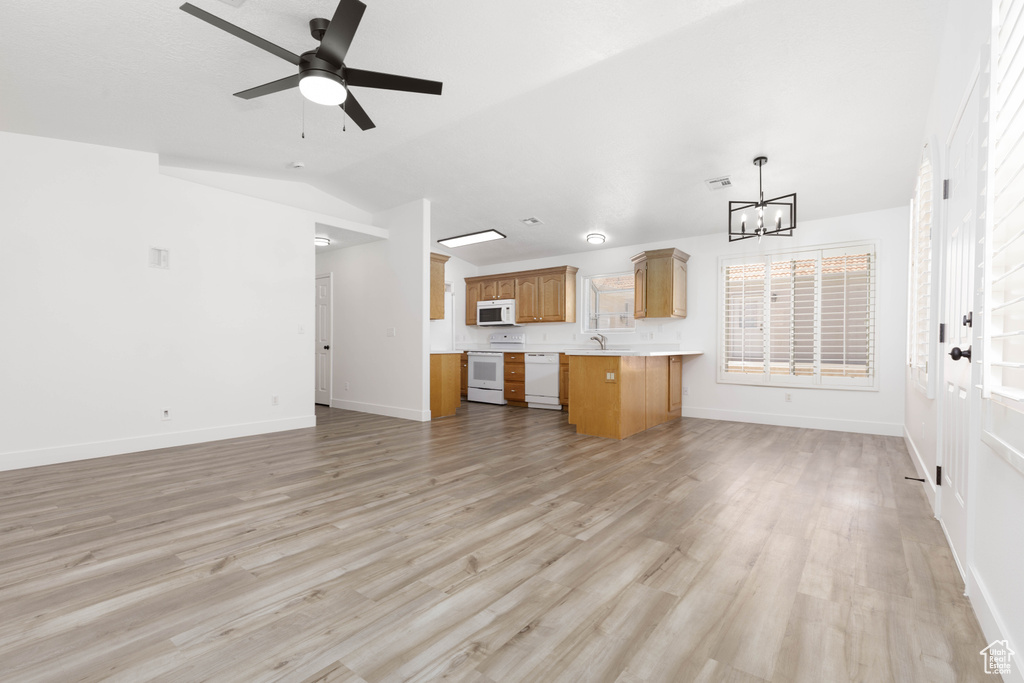 Unfurnished living room featuring a chandelier, lofted ceiling, light wood finished floors, and a ceiling fan