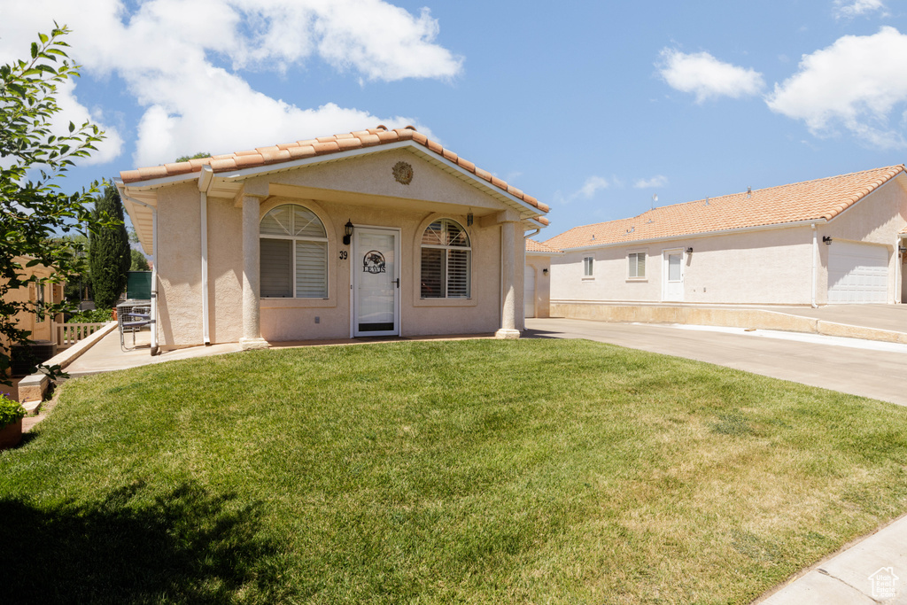 Mediterranean / spanish house with stucco siding, a front lawn, and a tile roof