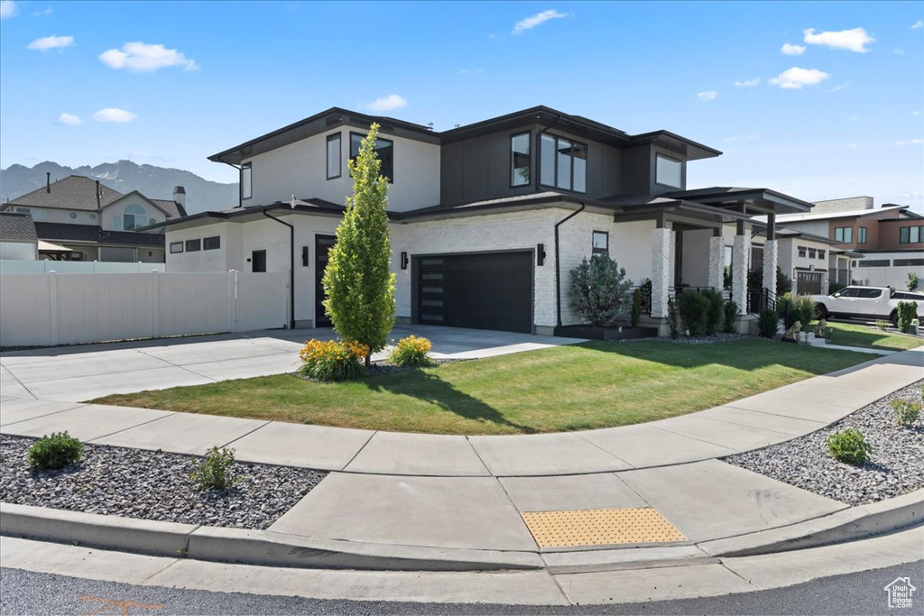 Modern home with an attached garage, concrete driveway, a residential view, and stucco siding